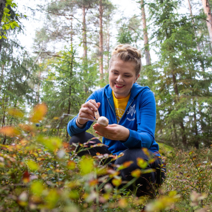 Nuori nainen metsässä, puhdistaa poimimaansa sientä